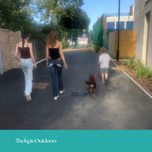 3 children and a dog on a lead walking together, taken from behind.