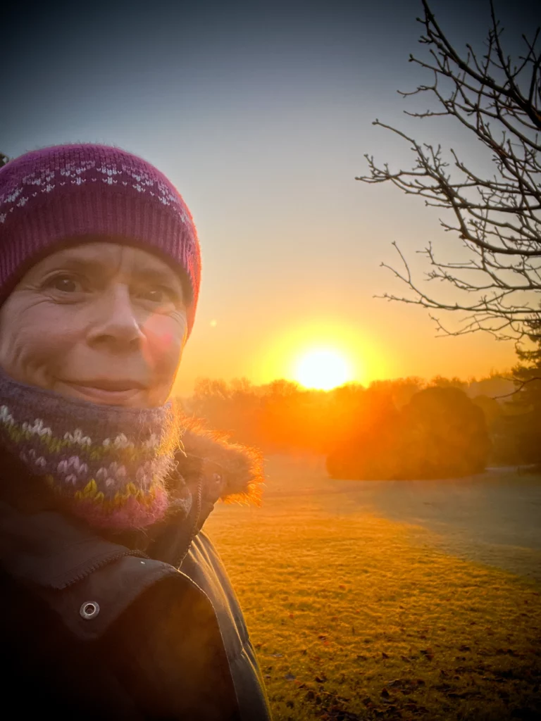 Midlife woman in warm wintry clothing with sunrise