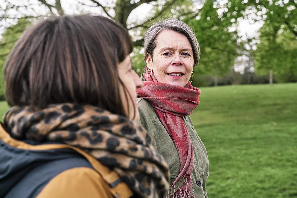 Midlife woman walking outdoors with a life coach, talking and reflecting in nature