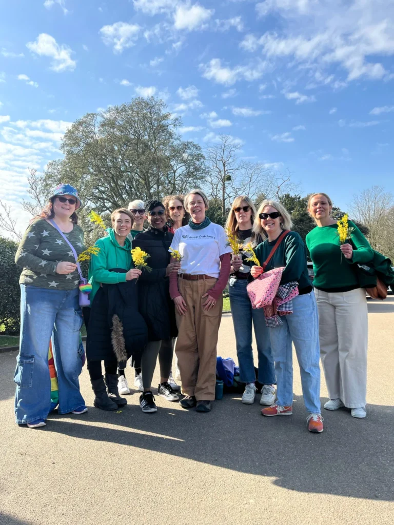Group of midlife women smiling and holding Mimosa for International Women's Day